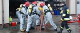 Strażacy w lekkich ubraniach chemicznyc podczas ćwiczeń z ratownictwa chemiczno-ekologicznego