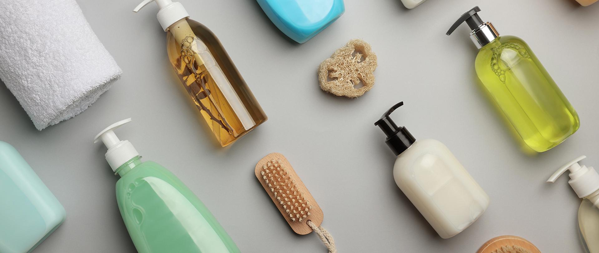Flat lay composition with bottles of liquid soap on grey background