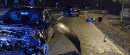 Uszkodzone pojazdy na jezdni po kolizji drogowej, jezdnia posypana sorbentem. Pora nocna.
