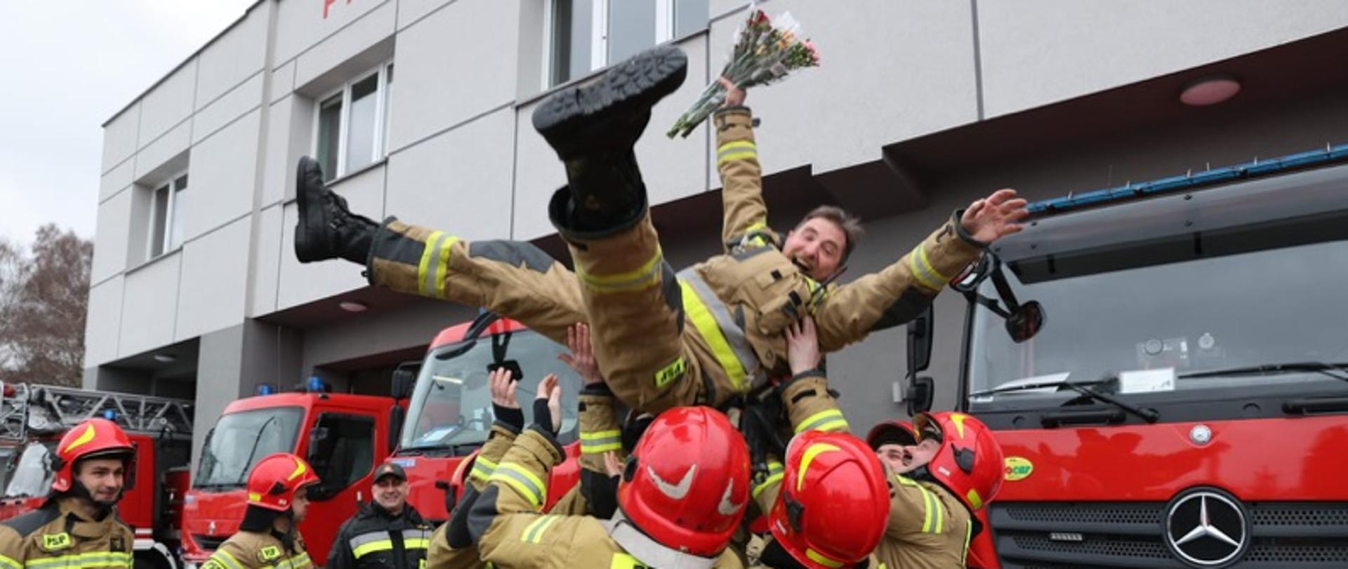 Ostatnia zmiana służby - koledzy ze zmiany służbowej podrzucają już szczęśliwego strażaka-emeryta