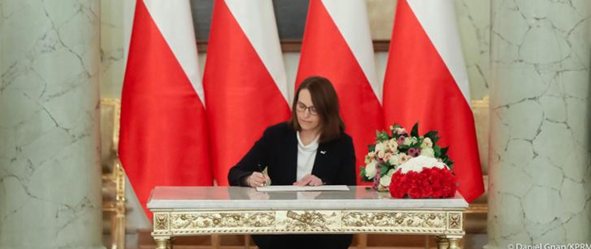 Jedna kobieta siedząca przy stoliku i podpisująca