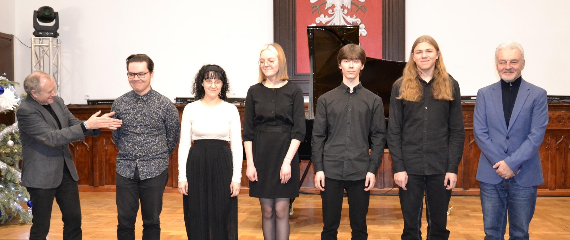 zdjęcie grupowe z koncertu muzyki fortepianowej w którym wystąpili studenci Akademii Muzycznej im. Grażyny i Kiejstuta Bacewiczów z Łodzi na scenie w Sali Królewskiej PSM MIelec