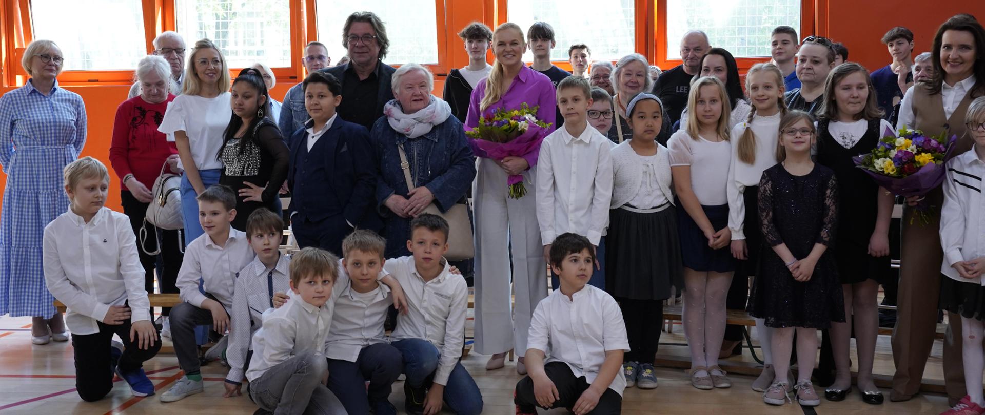 Zdjęcie zbiorowe, na sali stoi duża grupa ludzi, dzieci i dorosłych i pozuje do zdjęcia, wśród nich minister Barbara Nowacka