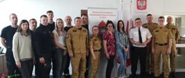Na zdjęciu grupa strażaków oraz pracowników cywilnych pozuje z przedstawicielką organizatora szkolenia i badań. 