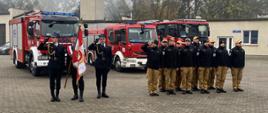 Zdjęcie przedstawia funkcjonariuszy KP PSP w Brodnicy podczas uroczystości upamiętniającej 105 rocznicę odzyskania niepodległości. Po lewo poczet flagowy. Za strażakami pojazdy gaśnicze JRG.