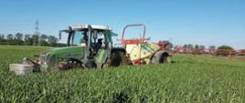 Zdjęcie przedstawia traktor z opryskiwaczem na polu