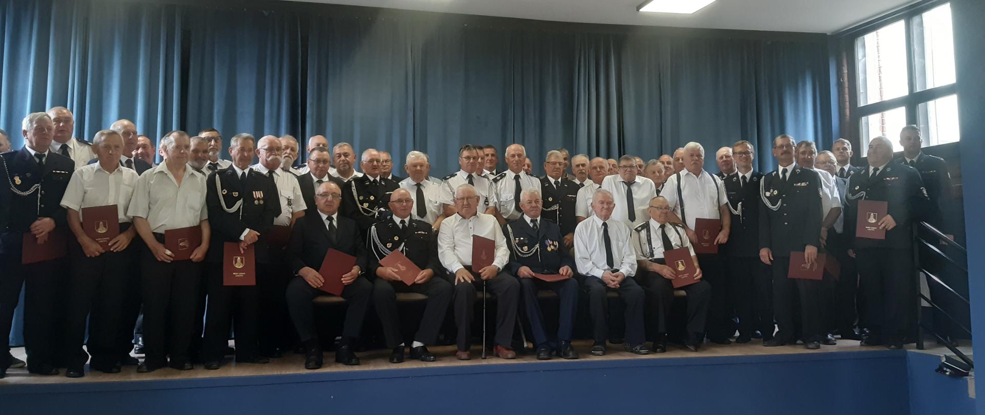 Wręczenie decyzji o przyznaniu świadczeń ratowniczych. Na zdjęciu znajdują się druhowie z terenu gminy Lisewo, którym przyznano świadczenia ratownicze. Zdjęcie wykonano w sali sesyjnej zlokalizowanej przy Zespole Szkół w Lisewie.