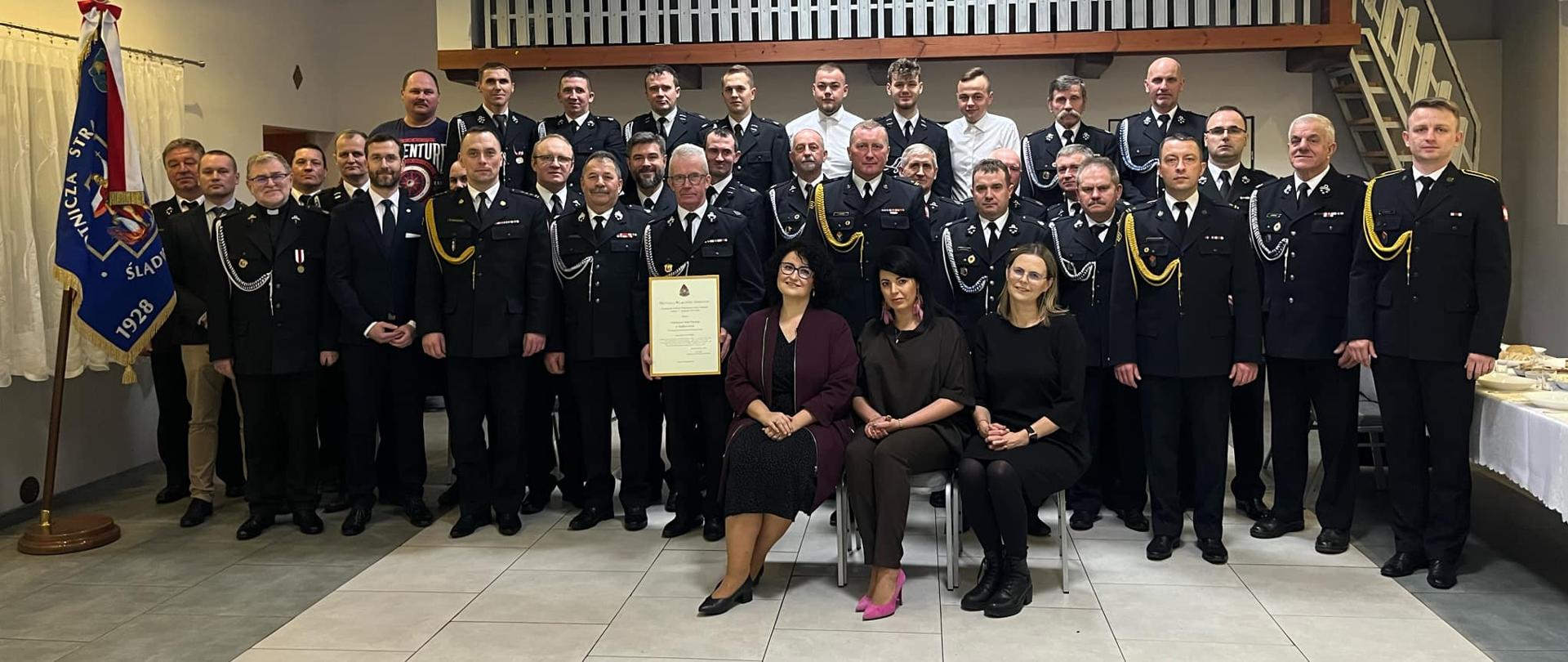 Pamiątkowe zdjęcie wykonane po uroczystości oficjalnego wręczenia decyzji włączającej OSP Ślądkowice do KSRG. Na zdjęciu członkowie jednostki OSP i goście.