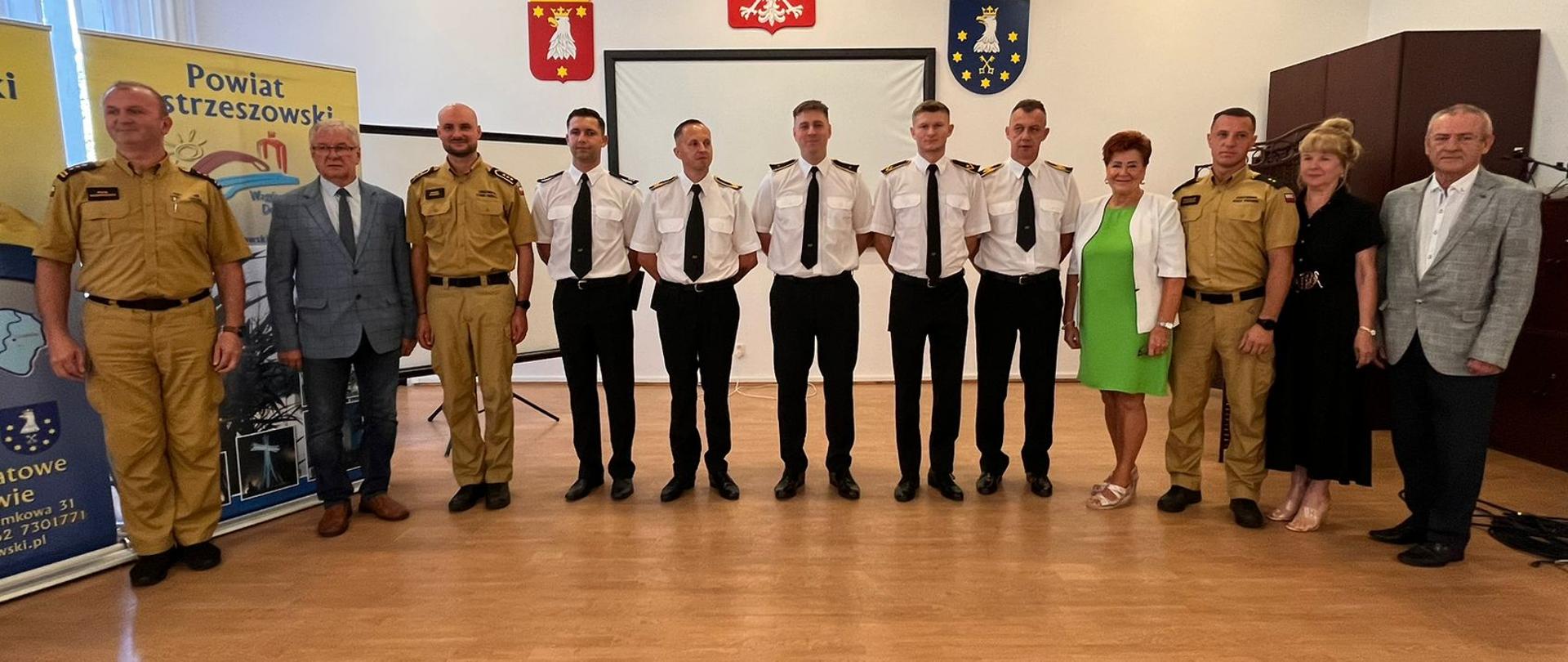 Strażacy wraz z starostwem stoją w sali sesyjnej