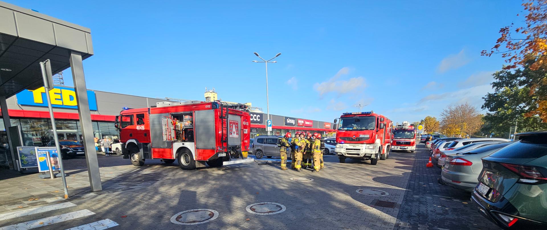 Strażacy podczas ćwiczeń dokonują gaszenia pojazdu i sklepu