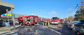 Strażacy podczas ćwiczeń dokonują gaszenia pojazdu i sklepu