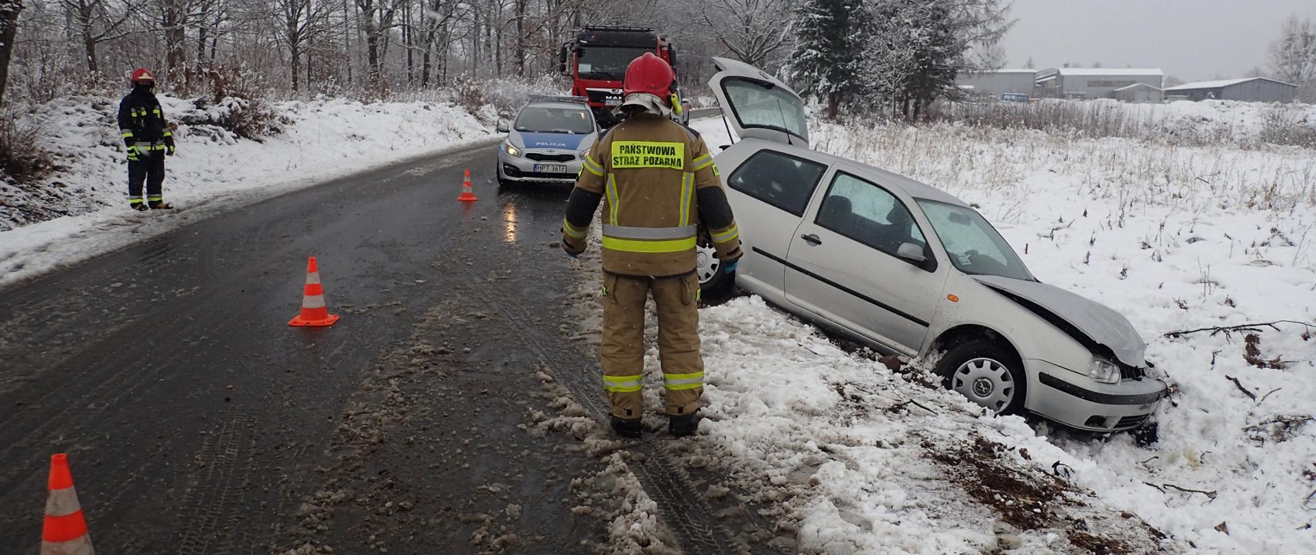Zdjęcie przedstawia strażaka w tyle uszkodzonego pojazdu. 