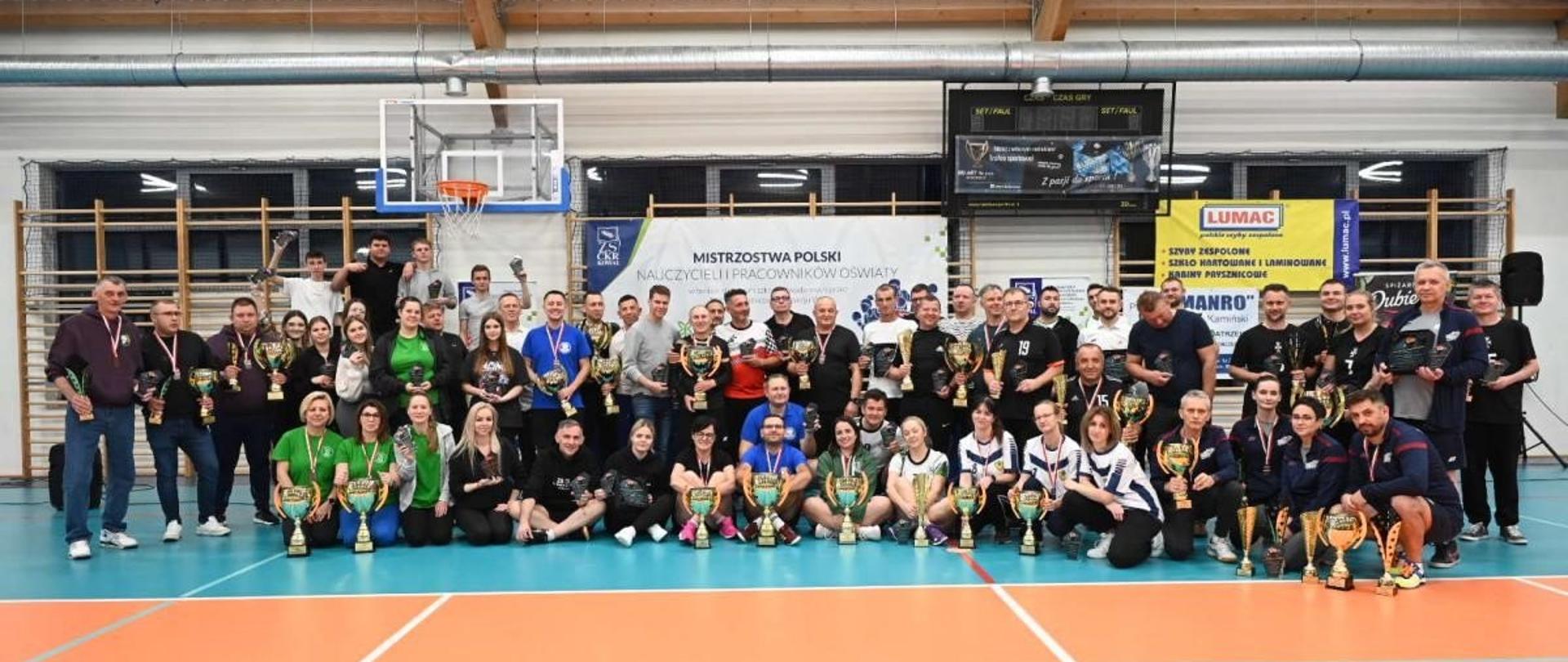 Fotografia grupowa z Mistrzostw Polski Nauczycieli i Pracowników Szkół prowadzonych przez Ministra Rolnictwa i Rozwoju Wsi. Zdjęcie grupowe zrobione w hali sportowej.