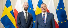 Od lewej ministrowie Carl-Oskar Bohlon i Tomasz Siemoniak stoją na tle flag: szwedzkiej, polskiej i unijnej 