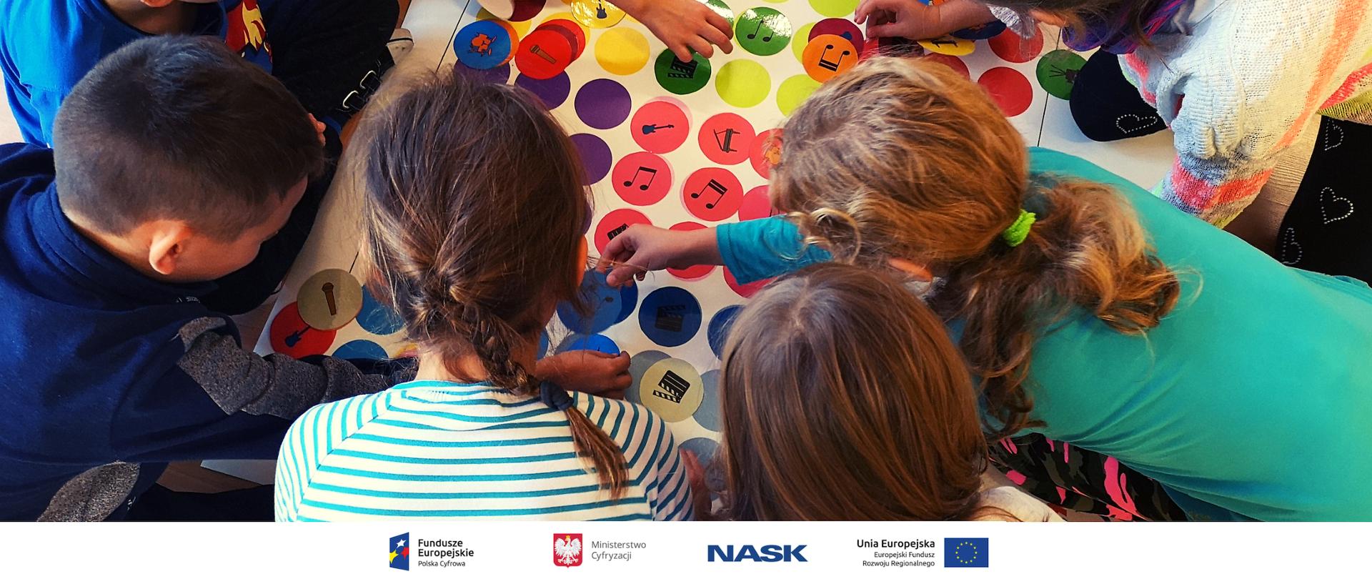 Dzieci bawią się w grę w planszową związaną z programowaniem. 