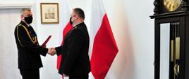 Zdjęcie przedstawia pomorskiego komendanta wojewódzkiego PSP st. bryg. Piotra Sochę wręczającego decyzję o powołaniu na stanowisko zastępcy komendanta powiatowego PSP w Malborku kpt. Damianowi Tomaszewskiemu.