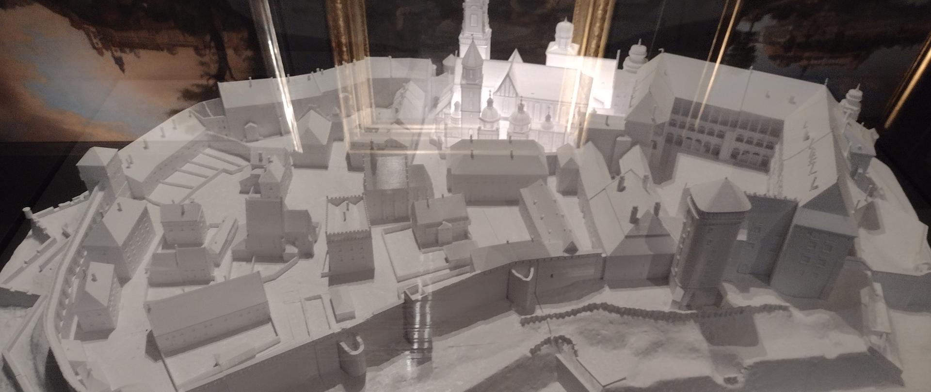 Na zdjęciu w szklanej gablocie biała makieta wzgórza wawelskiego