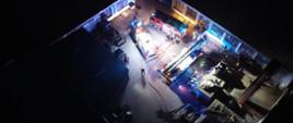 Zdjęcie przedstawia widok z góry na którym widać trzy pojazdy pożarnicze oraz oraz strażaków biorących udział w działaniach gaśniczych.