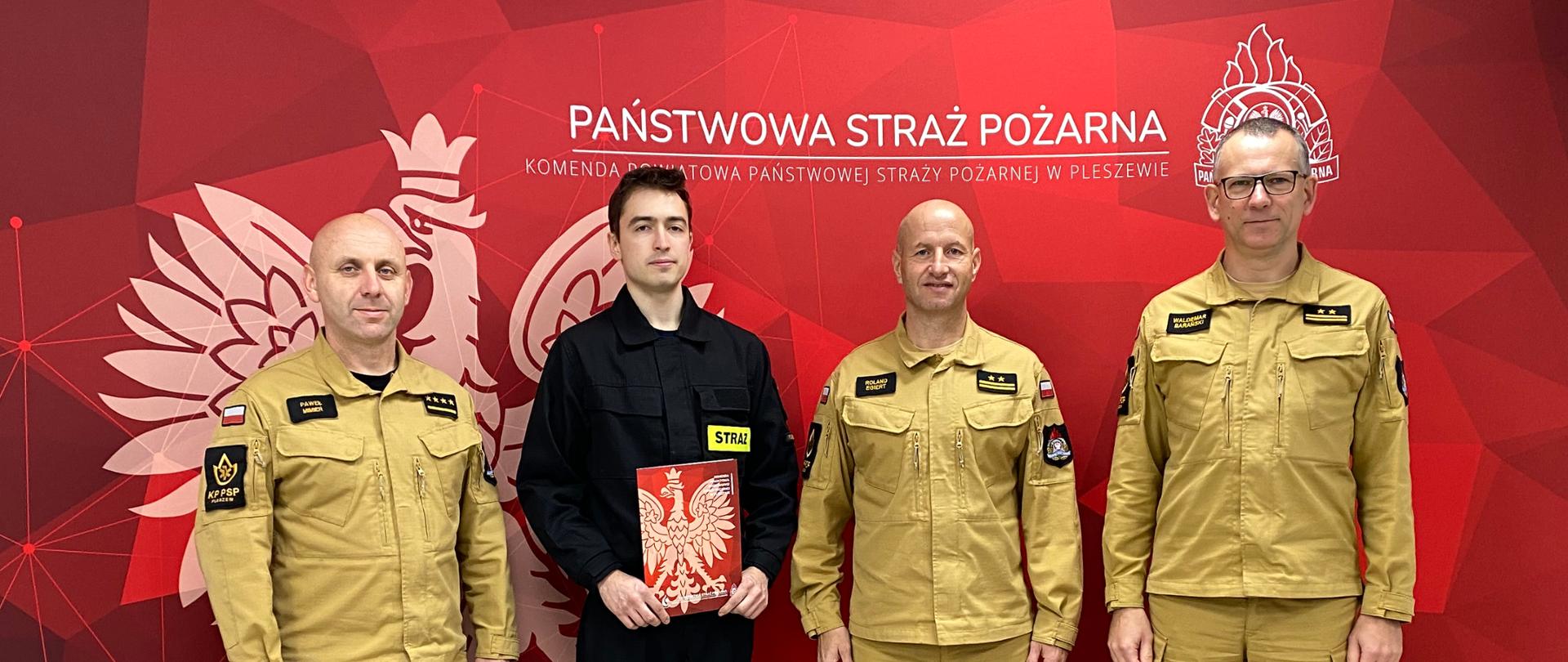 Strażacy na tle baneru KP PSP Pleszew