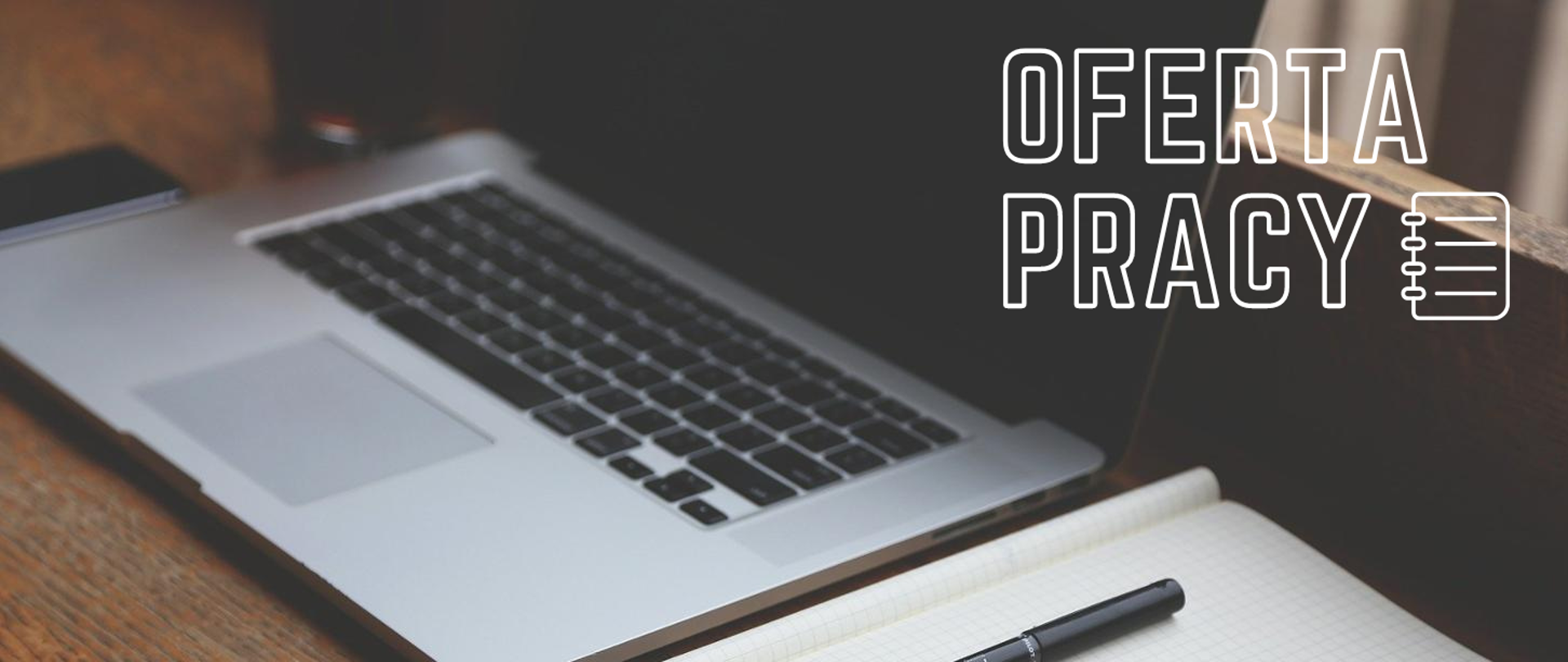 Laptop oraz zeszyt z długopisem na biurku