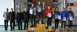 XIII Ogólnopolski Halowy Turniej Drabin Hakowych w Sokołowie Podlaskim - Najlepsi zawodnicy stoją na podium, otrzymali puchary, dyplomy oraz nagrody. rzeczowe Razem z nimi stoją strażacy .