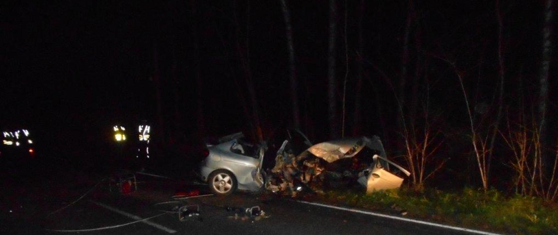 Zdjęcie przedstawia samochód Renault po uderzeniu w drzewo na poboczu drogi