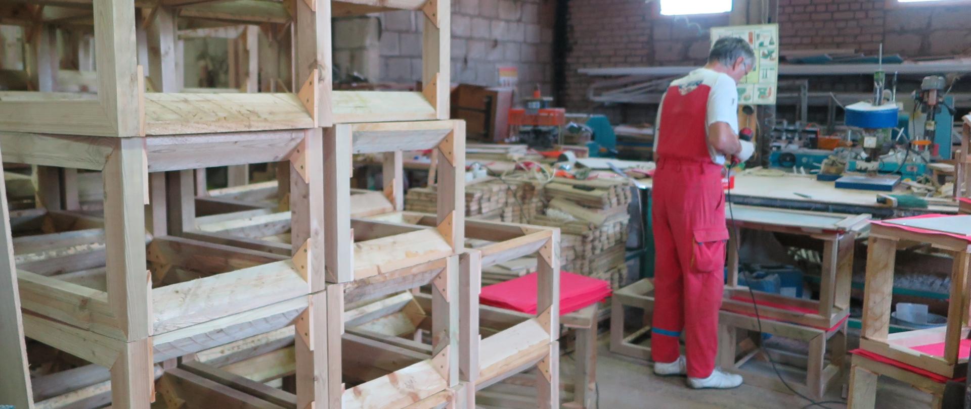 mężczyzna stoi przy stole i trzyma w ręku narzędzie 