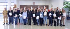 Pamiątkowe zdjęcie grupowe uczestników szkolenia dla inspektorów ochrony przeciwpożarowej (26 osób) w towarzystwie p.o. Komendanta Centralnej Szkoły PSP, kobiety oraz dwóch oficerów CS PSP