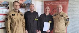 Zdjęcie przedstawia czterech strazaków podczas wreczenia nagrody za 20 lat służby i pracy