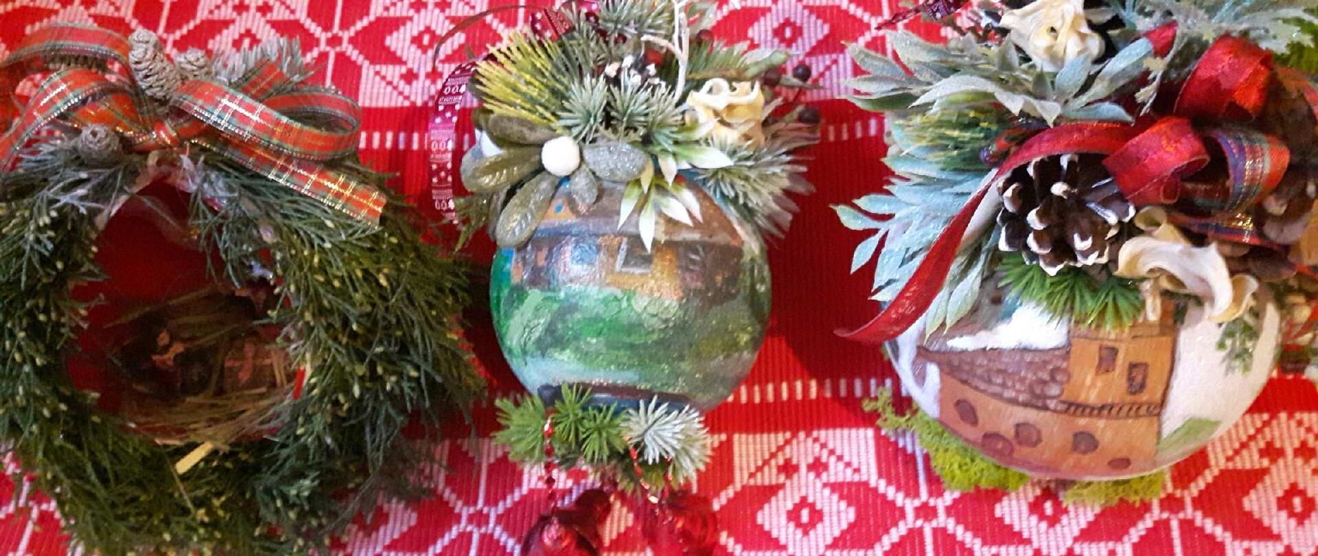 Na zdjęciu trzy świąteczne dekoracje umieszczone na czerwono-białym materiale ze wzorami o charakterze świątecznym:
Po lewej zielony wieniec ozdobiony czerwono-zieloną kratką na górze.
W centrum kulista ozdoba pokryta malowanymi scenami krajobrazu, budynków, u góry ozdobiona różnorodnymi zielonymi roślinami i białymi kwiatami.
Po prawej kulista ozdoba przedstawia malowane scenę zimowego krajobrazu z budynkiem, również ozdobiona różnorodnymi zielonymi roślinami, szyszkami i czerwono-zieloną wstążką w kratkę.