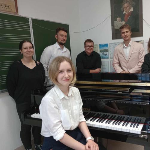 Zdjęcie sześciu osób przy fortepianie, trzy dziewczyny i trzech chłopaków.