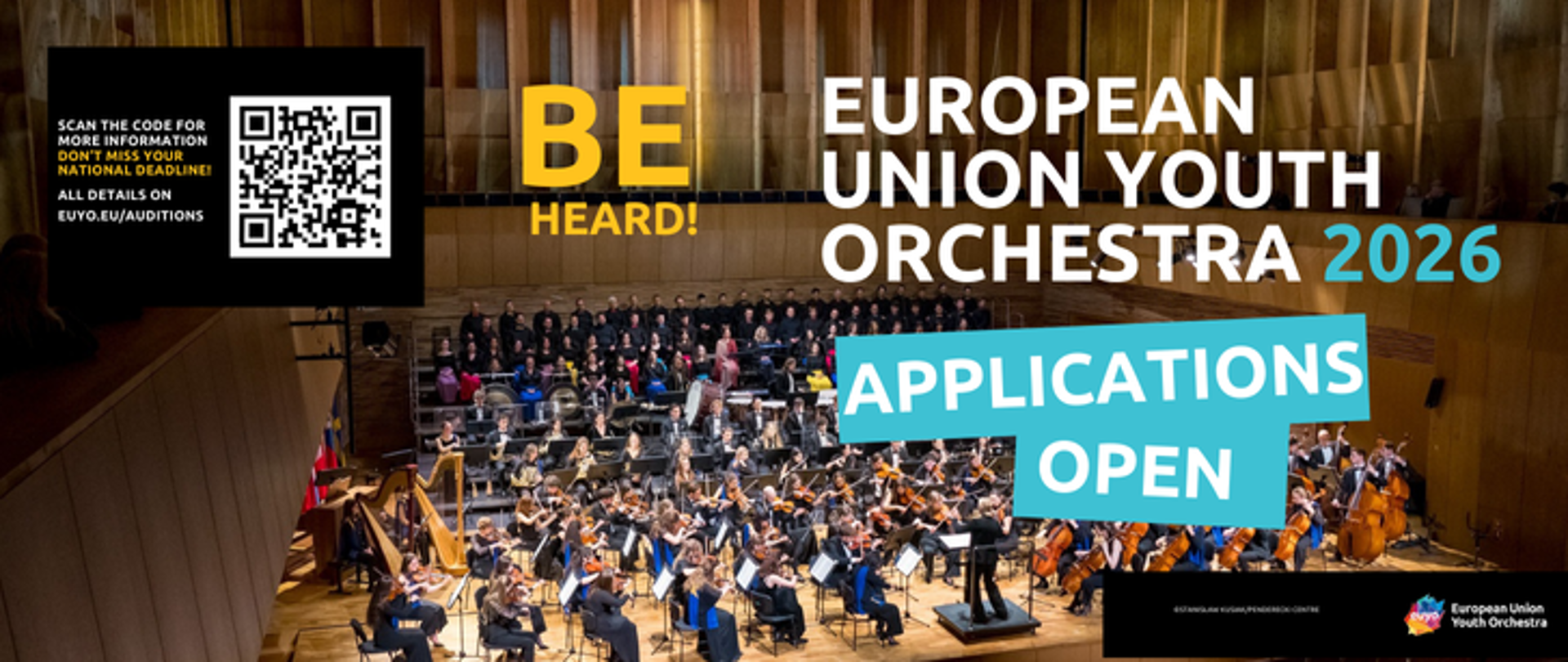Baner informacyjny z kodem QR umieszczonym w lewej, górnej części. Tło stanowi zdjęcie European Union Youth Orchestra podczas występu na scenie filharmonii.