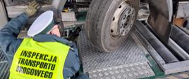 Samochód ciężarowy stoi kołami pierwszej osi na tzw. „szarpakach" Mobilnej Jednostki Diagnostycznej. Inspektor wielkopolskiej Inspekcji Transportu Drogowego sprawdza luzy w układzie kierowniczym pojazdu.