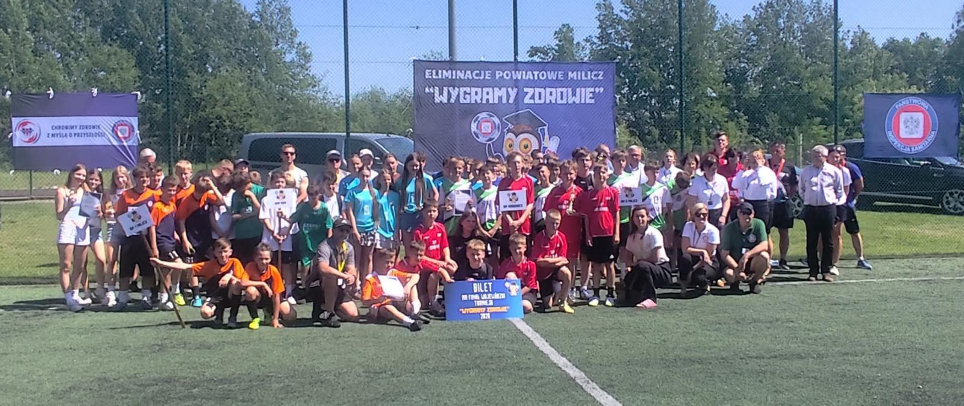 Uczestnicy turnieju pozują do zdjęcia na boisku piłkarskim