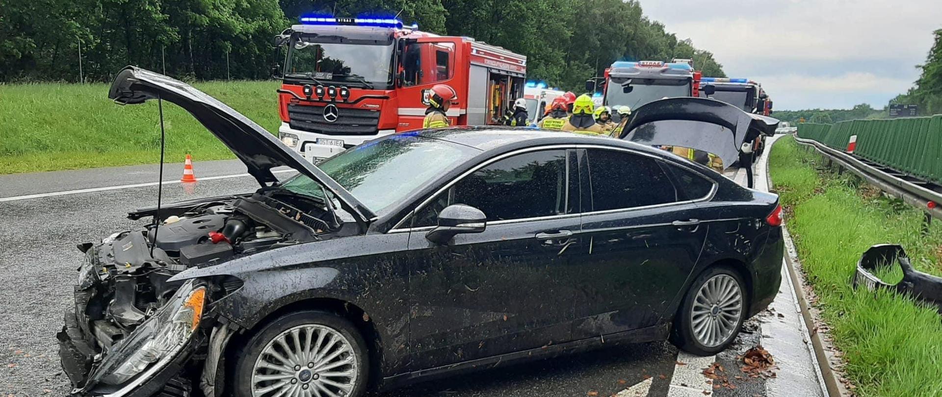 Na zdjęciu znajduje się wrak rozbitego samochodu osobowego oraz samochody pożarnicze i strażacy
