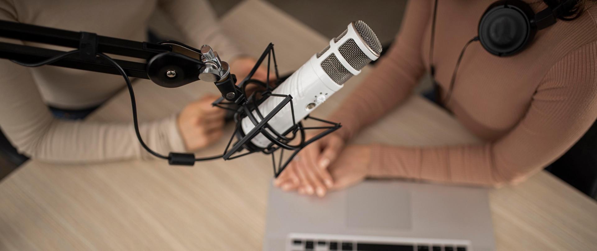 Widok z góry na ręce dwóch kobiet, komputer i mikrofon