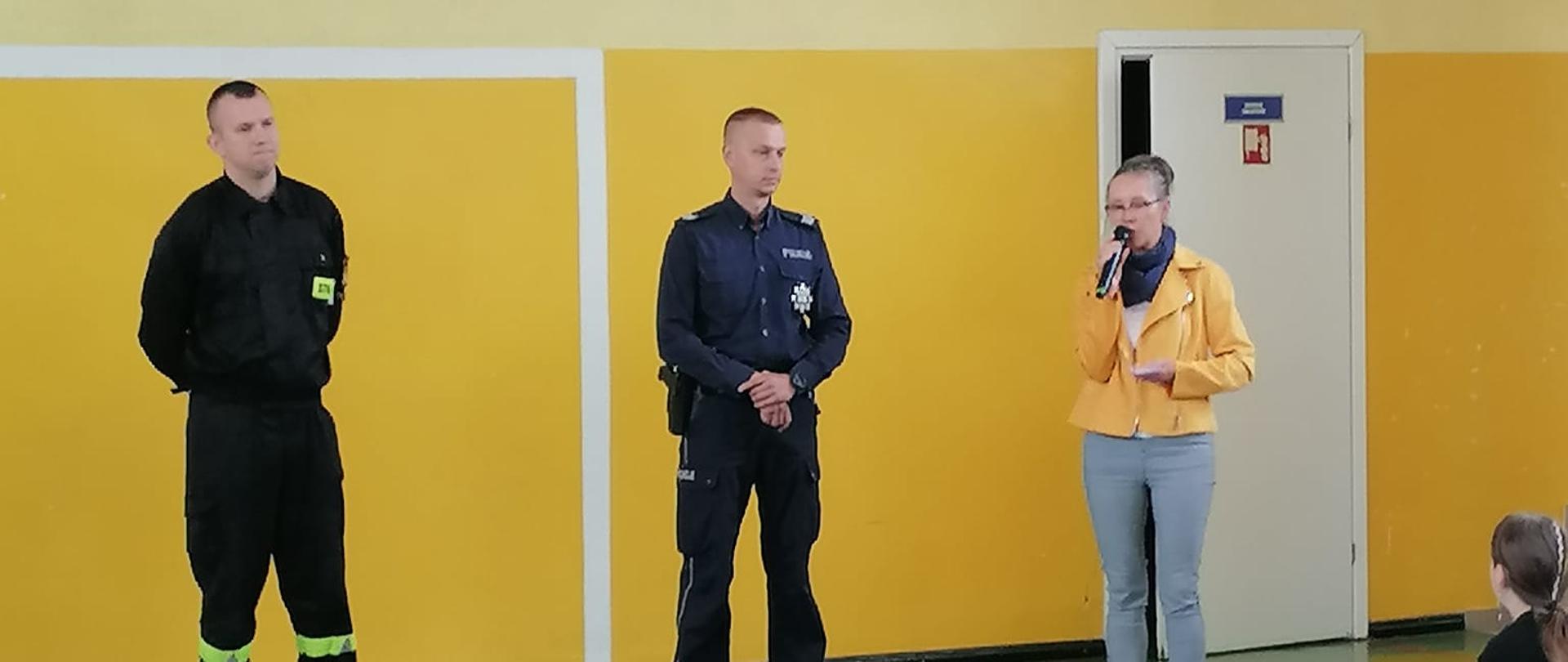 strażak, policjant , pani nauczycielka stoją przed grupka dzieci 