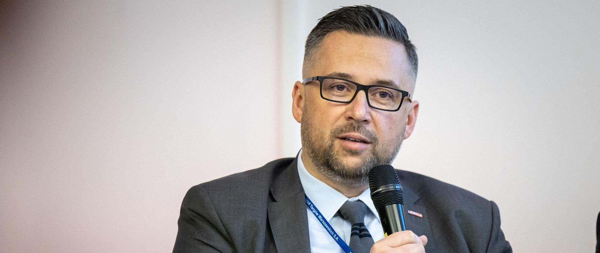 Wiceminister Marcin Kulasek przemawia do mikrofonu. 