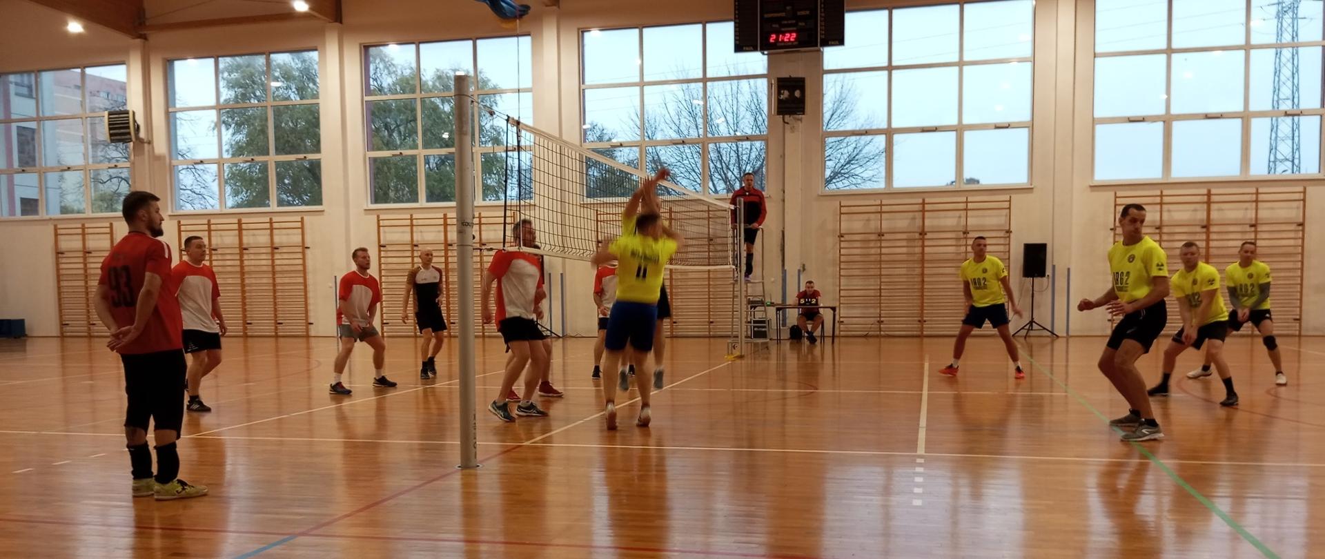 Mecz pomiędzy drużynami JRG2 i SP PSP Bydgoszcz. JRG2 po prawej w żółtych koszulkach, SP PSP po lewej w czerwono białych koszulkach. Mecz odbywa się w sali gimnastycznej.