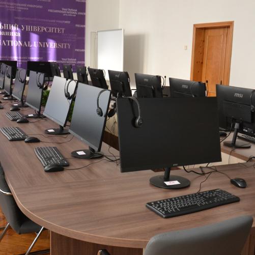 Sala komputerowa z licznymi stanowiskami komputerowymi.