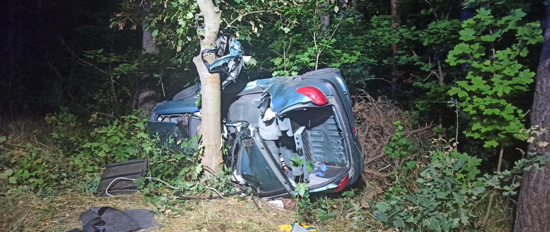 Na zdjęciu widać rozbity pojazd oparty o drzewo.