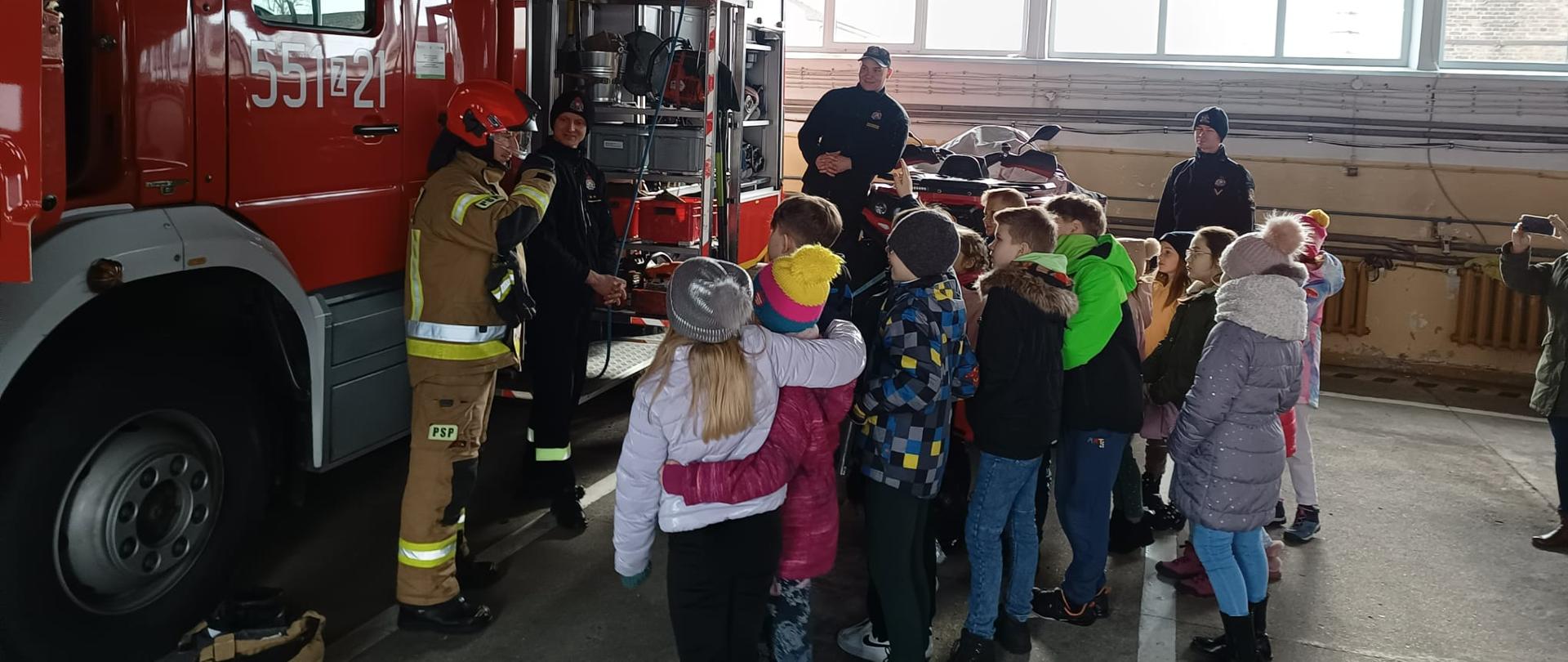 Zdjęcie przedstawia pokaz sprzętu dzieciom z półkolonii przez strażaków