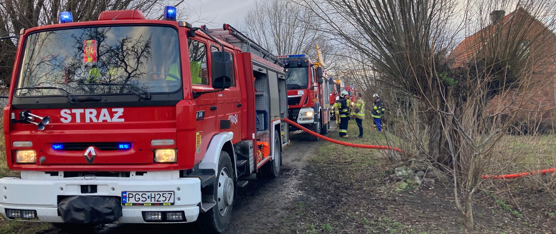 Samochody pożarnicze podczas pożaru stoją na drodze dojazdowej
