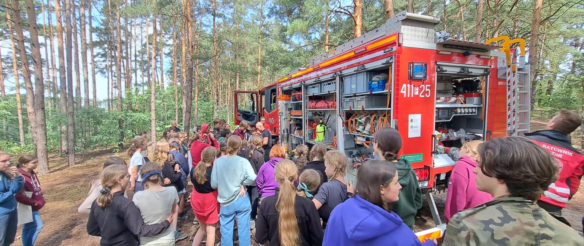 Na zdjęciu widać samochód gaśniczy i zebraną przy nim młodzież