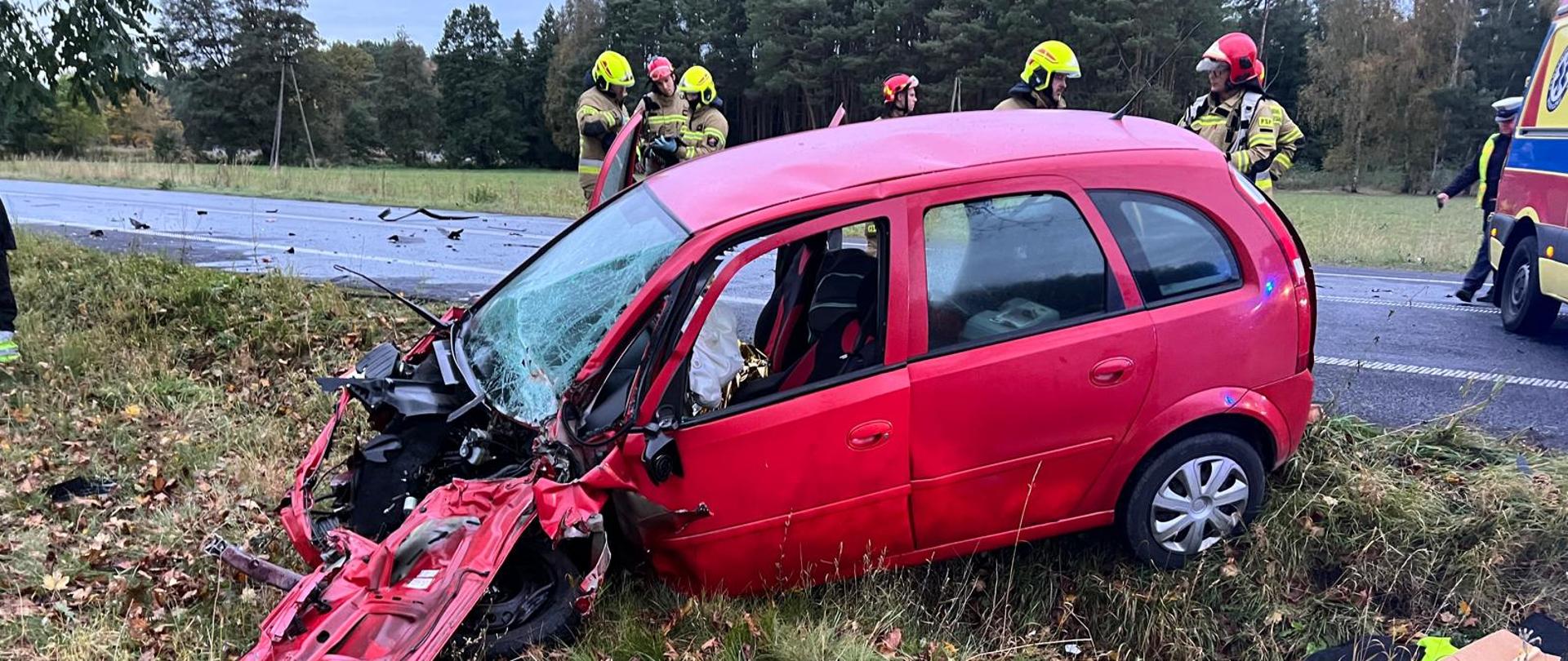 Samochód osobowy po wypadku oraz strażacy