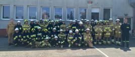 grupa strażaków – słuchaczy kursu, w tle budynek Komendy