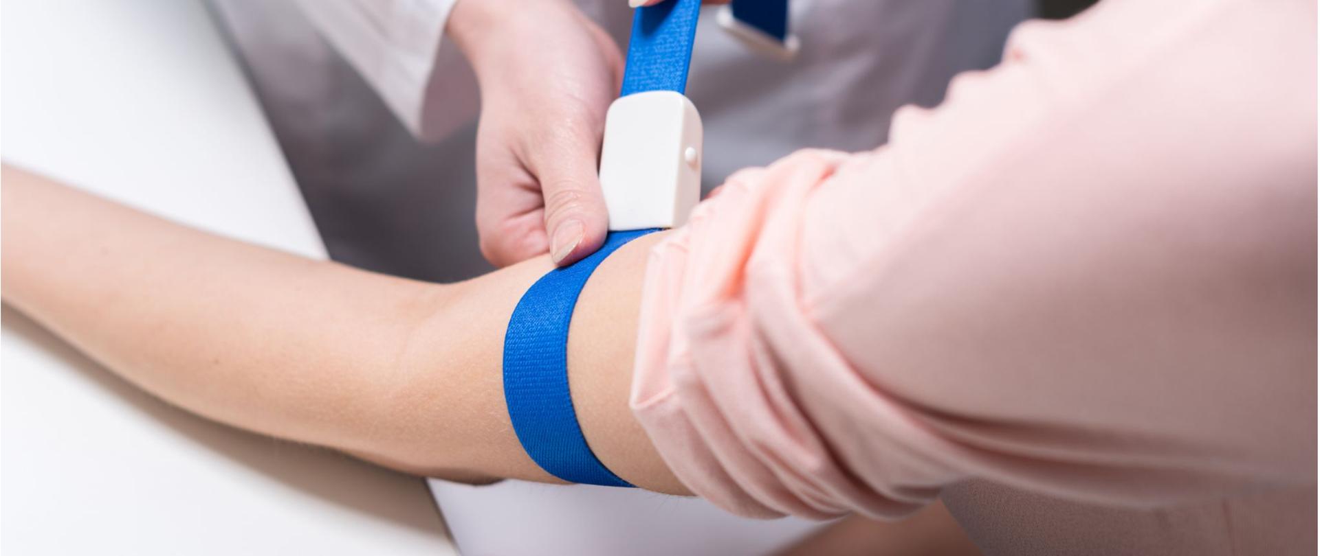 Na zdjęciu jest ukazana ręka pacjenta, na której lekarz zastosował ucisk na przedramieniu. 