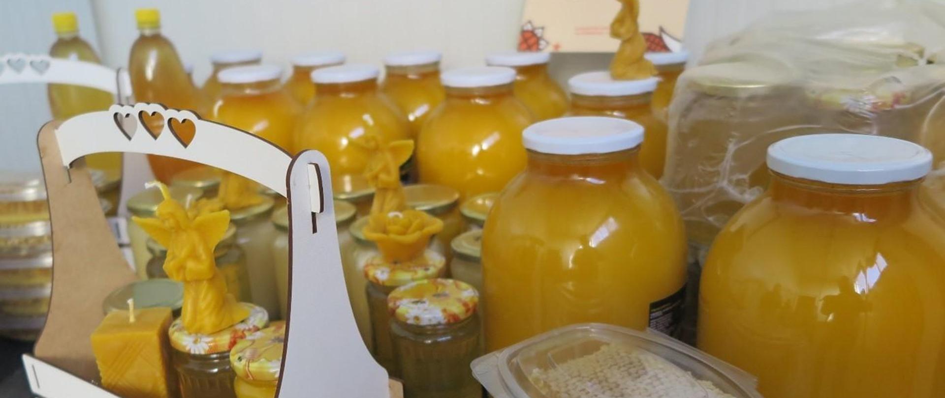 Wyroby pszczelarstwa w słoikach, plastikowych pudełkach i koszyku.