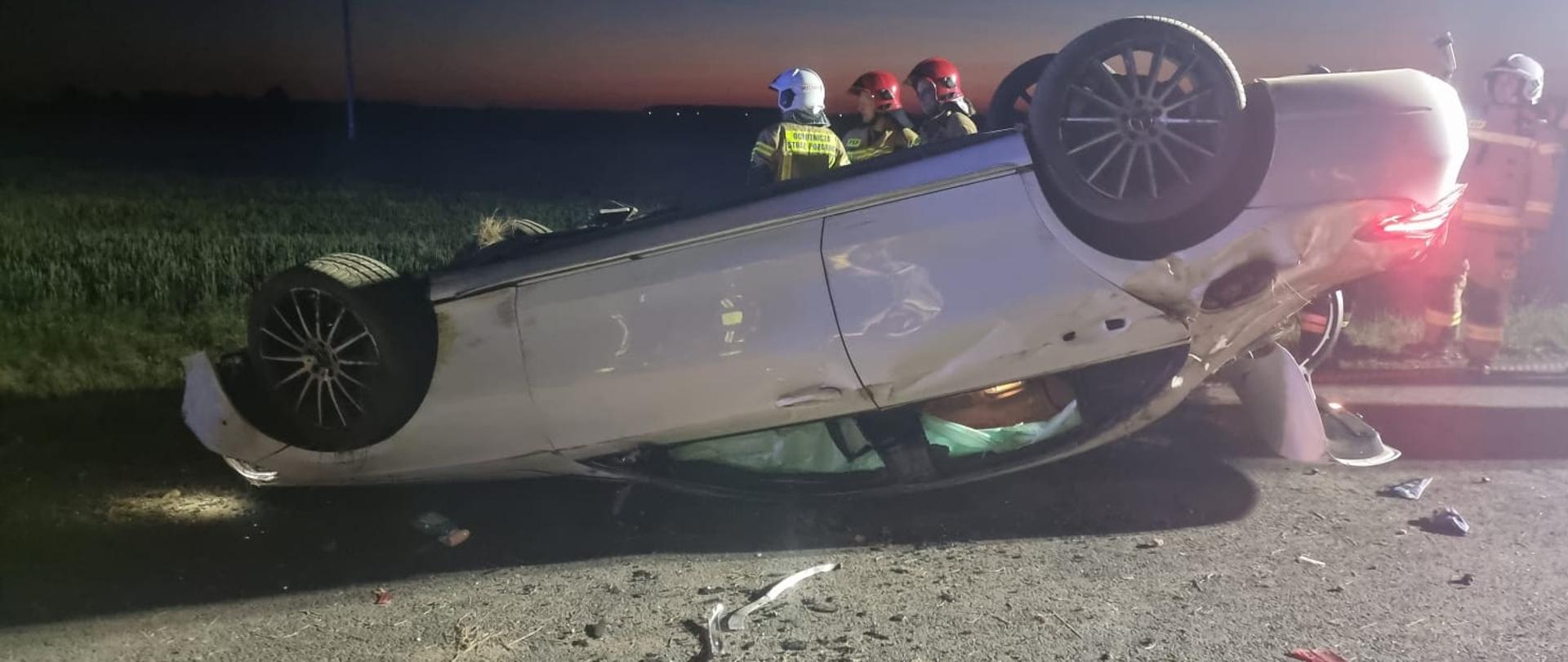 Widać samochodu osobowy w pozycji na dachu, jest na drodze, widok od boku