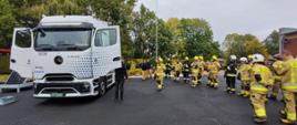 Grupa strażaków Ochotniczej Straży Pożarnej podczas praktycznego pokazu samochodu ciężarowego. W tym w przypadku jest to ciągnik siodłowy o napędzie elektrycznym.